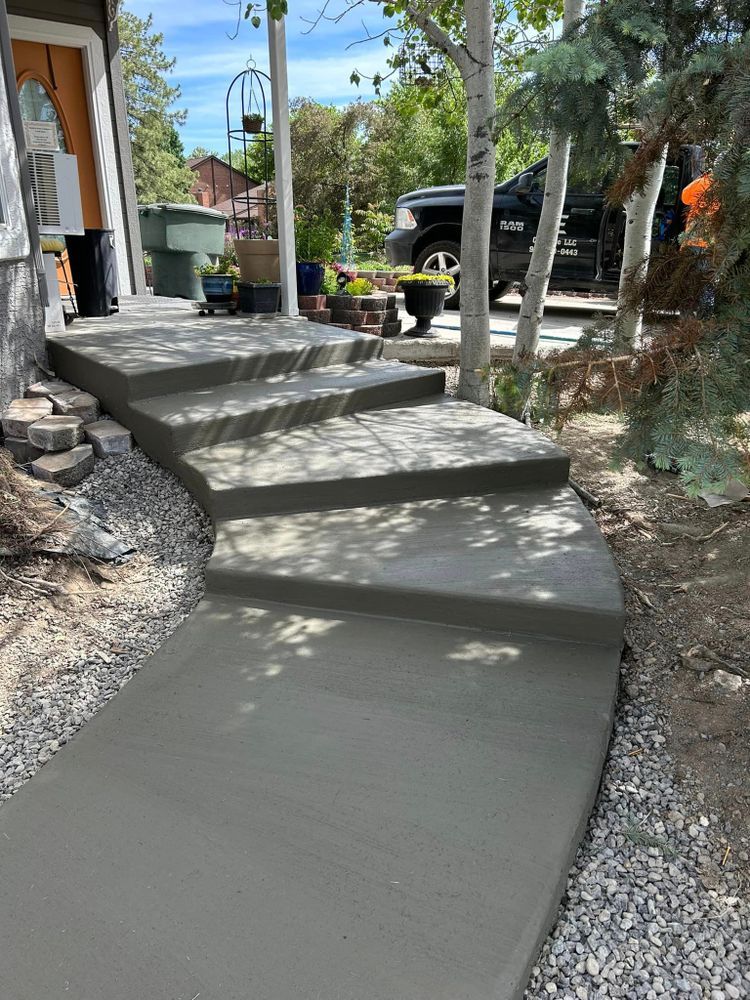 Newly poured concrete steps and walkway leading to a house, surrounded by gravel and trees.