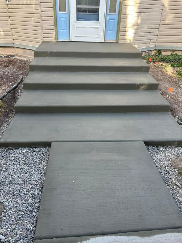 Newly poured concrete steps and walkway leading to a house's front door.