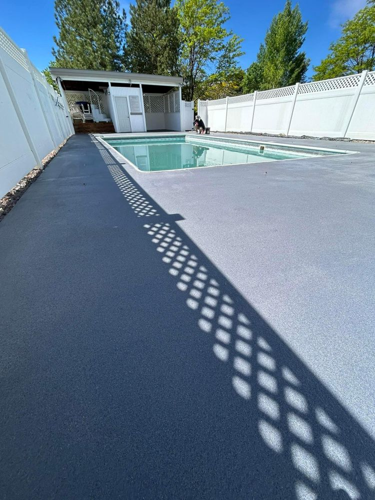 Gray concrete, blue pool, white fence, and shadows from a lattice fence in sunny setting.