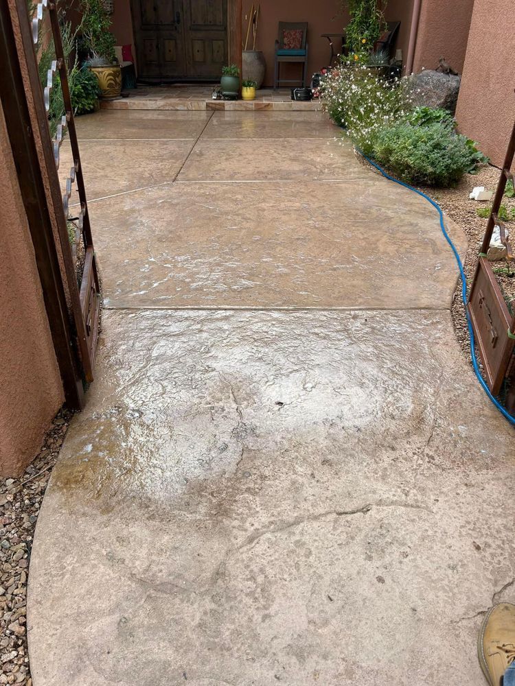 Concrete walkway, partially cleaned, leading to a doorway. Brown gate on the left.