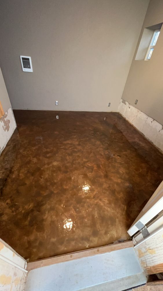 Newly installed metallic epoxy floor in a room with beige walls and exposed framing.