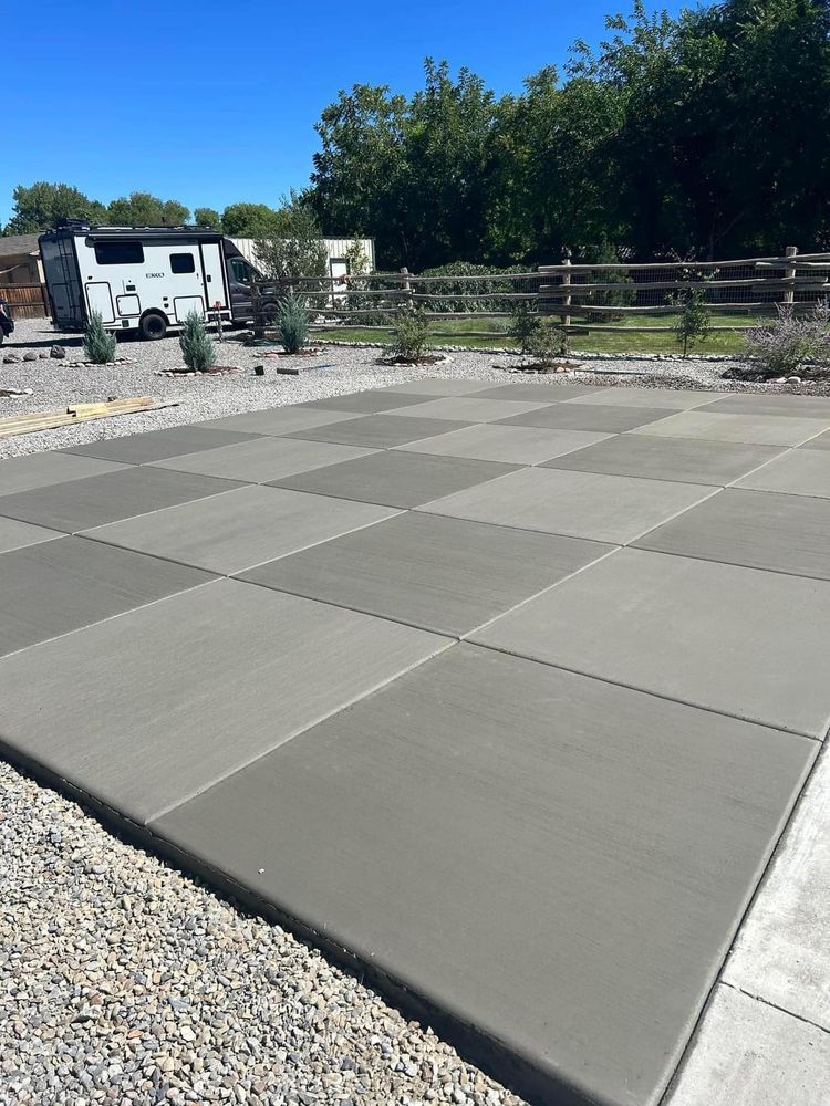Checkered concrete patio with gravel border, small plants, and a recreational vehicle.