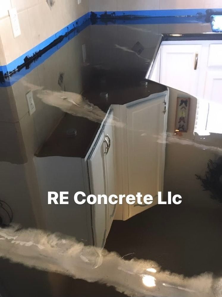 Epoxy-coated concrete countertops in a kitchen with white cabinetry.