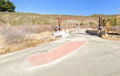 Asphalt road leading to a wooden archway entry, with a painted red area in the center.