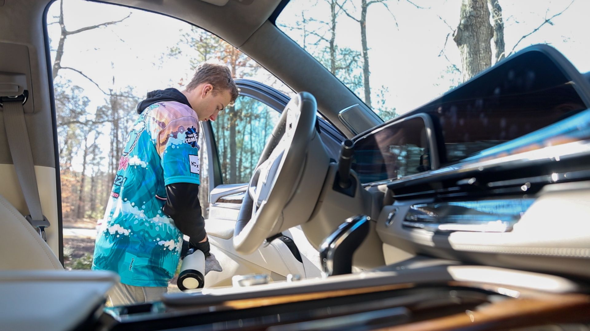 A man is cleaning the interior of a car with a vacuum cleaner.