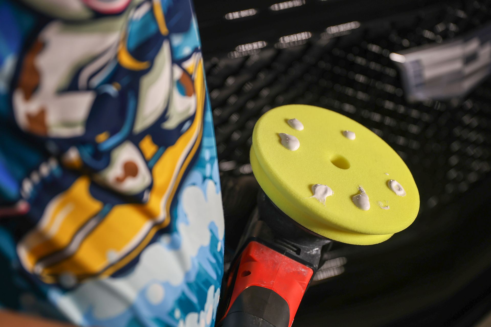 A person is holding a yellow polishing pad in front of a keyboard.
