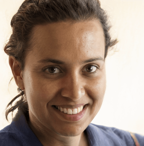 Woman smiling, brown eyes, dark hair pulled back, wearing a blue shirt.