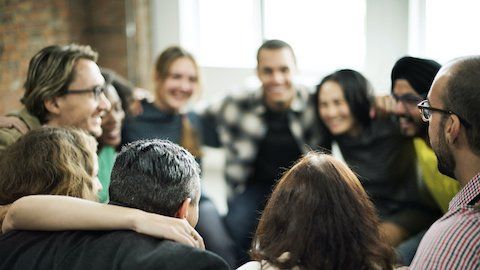 A group of employees standing in a circle with their arms around each other participating in a team building exercise.