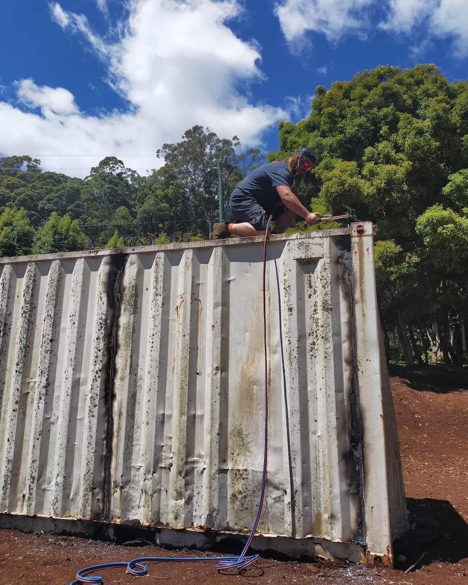 A Man Is Kneeling On Top Of A Shipping Container — East Coast Metal Recycling In Logan, QLD