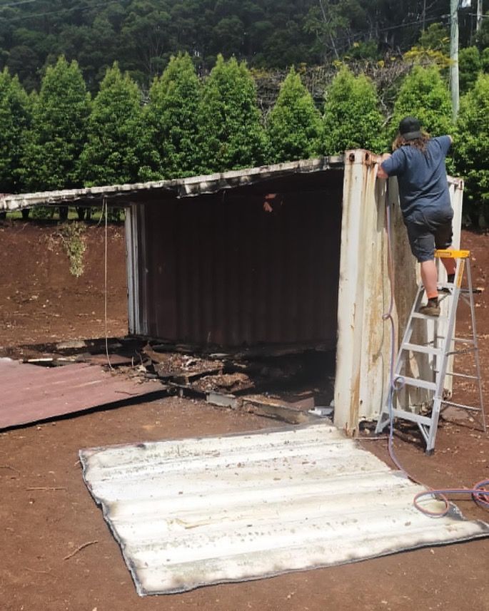 A Man On A Ladder Is Working On A Shed — East Coast Metal Recycling In Pimpama, QLD