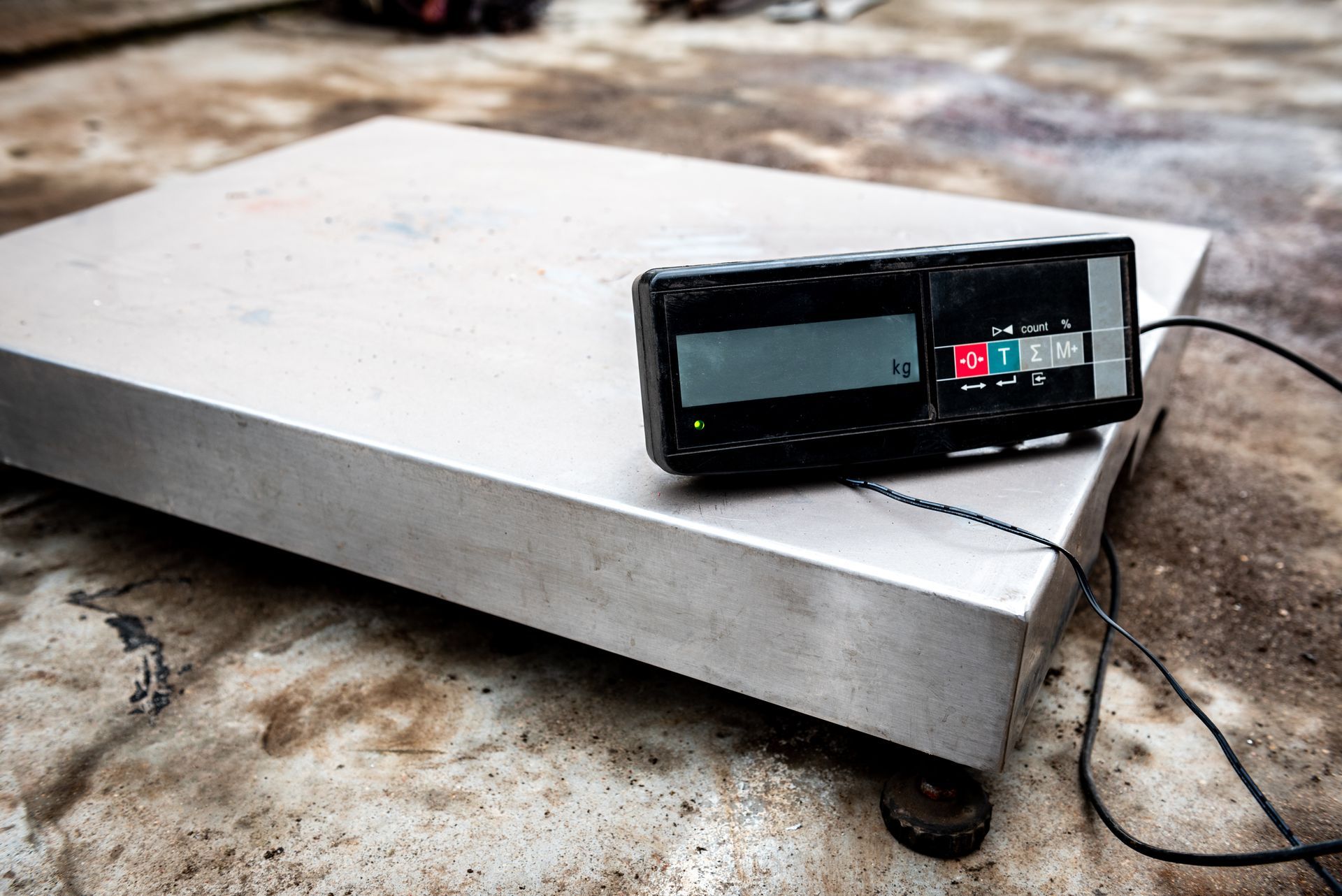 Industrial platform scale with a digital display indicator on a concrete floor.