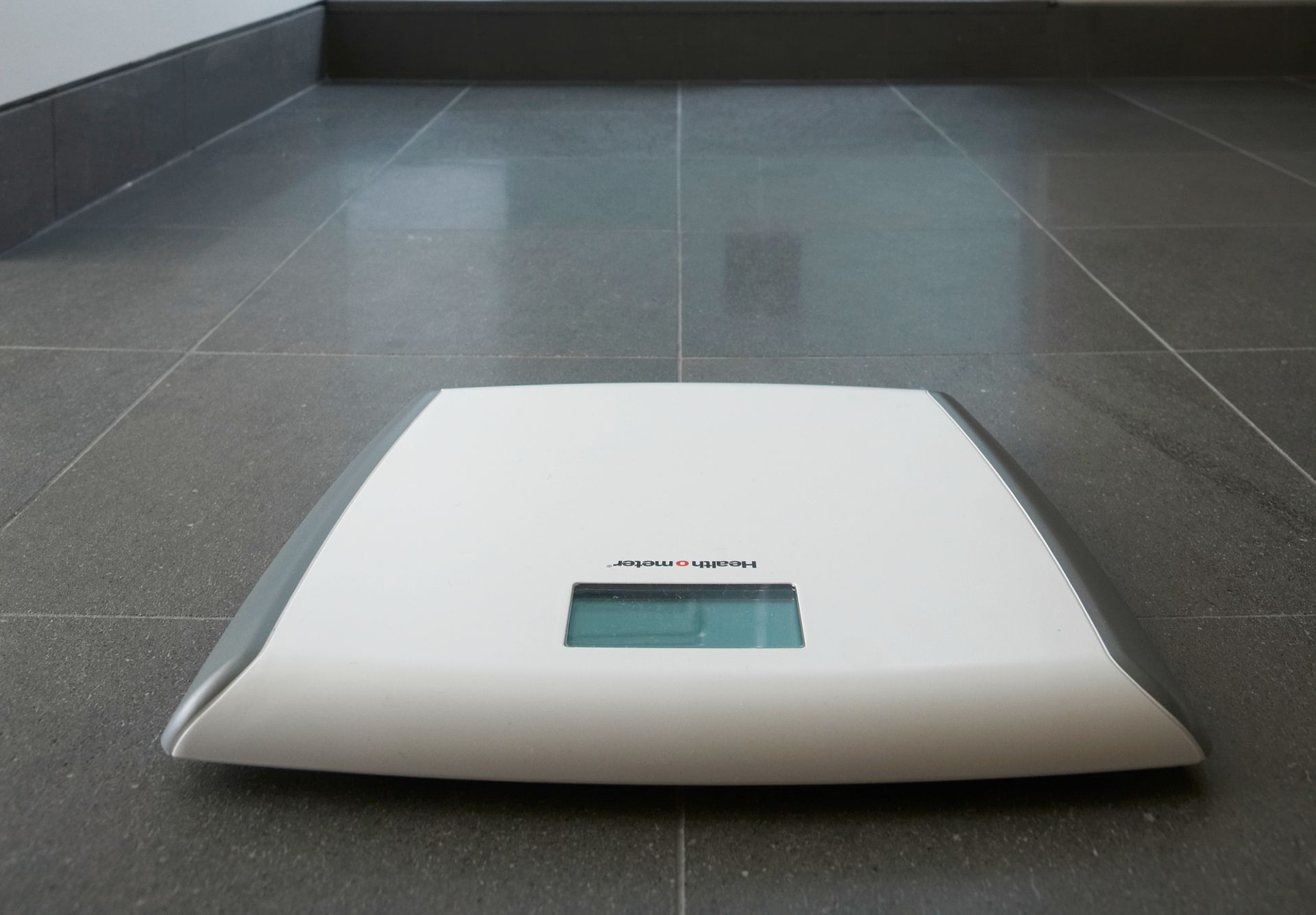 White and Silver Digital Bathroom Scale on A Gray Tiled Floor. White and Silver Digital Bathroom Scale on A Gray Tiled Floor.