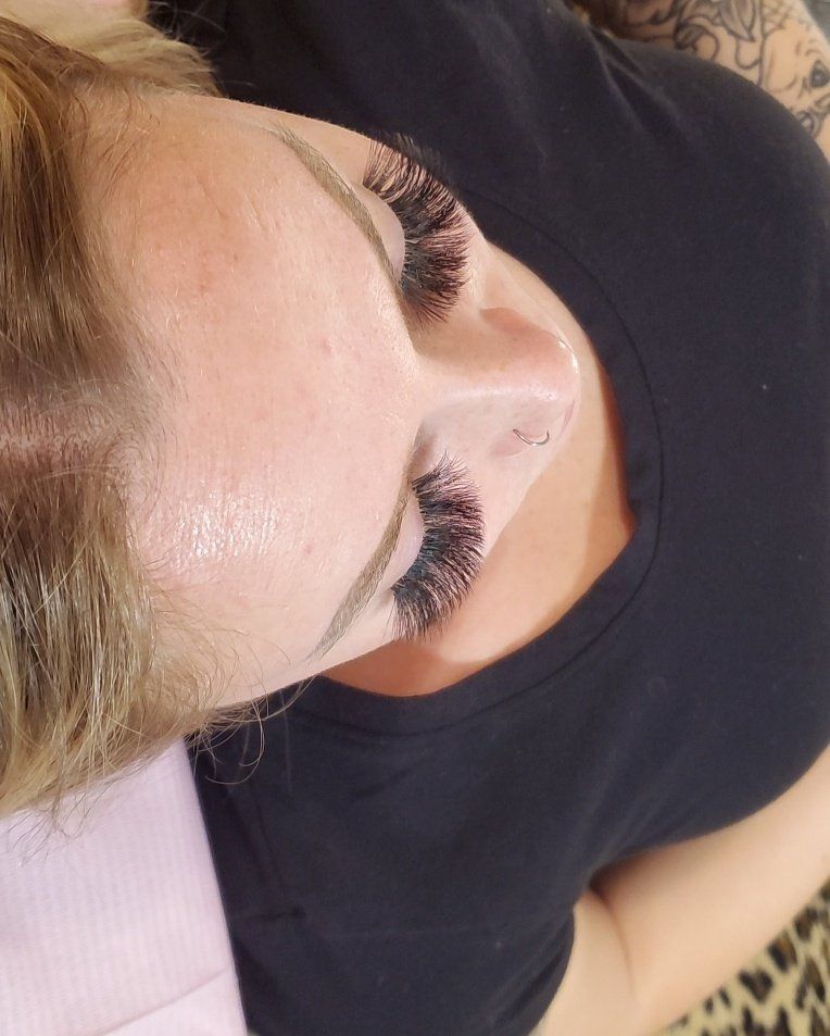 Woman with long, dark eyelashes, lying down with a black shirt on a leopard-print surface.