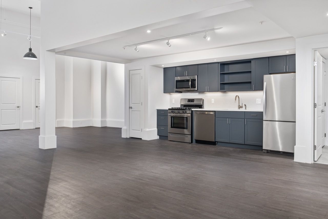Open-concept kitchen with stainless steel appliances and gray cabinetry.