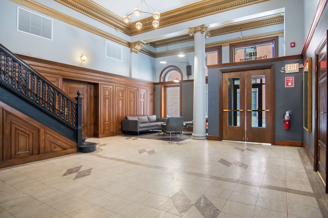 Interior community lobby with wood-paneled walls, staircase, columns, and seating.