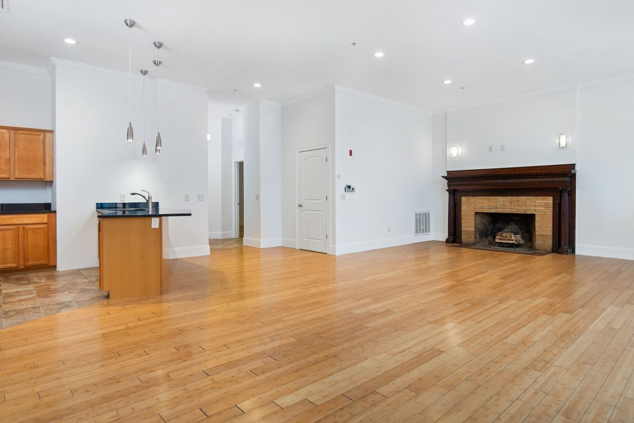 Open living area with hardwood floors, kitchen island, and brick fireplace.