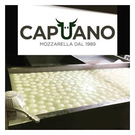 Il logo della mozzarella Caputo sopra un vassoio di mozzarelline fresche in un caseificio.