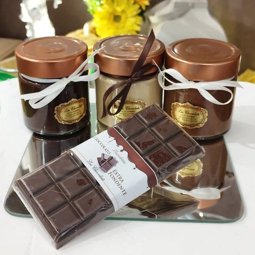 Barattoli di cioccolato con nastro e una tavoletta di cioccolato su una superficie riflettente.