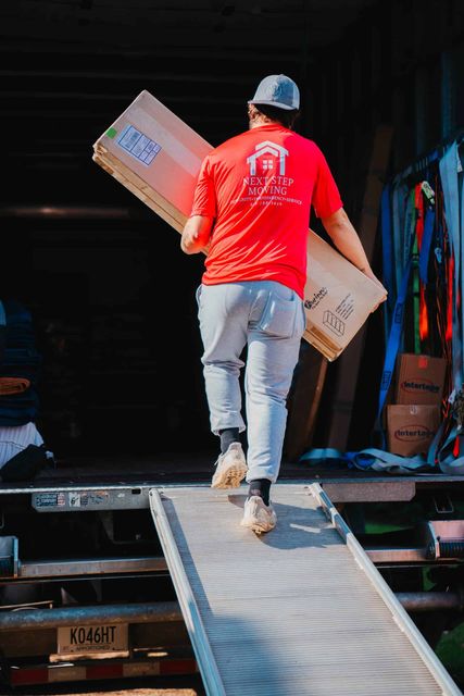A man in a red shirt is carrying a box on a ramp.