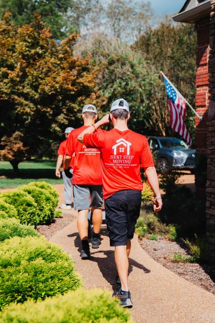 A group of men in red shirts are walking down a sidewalk.