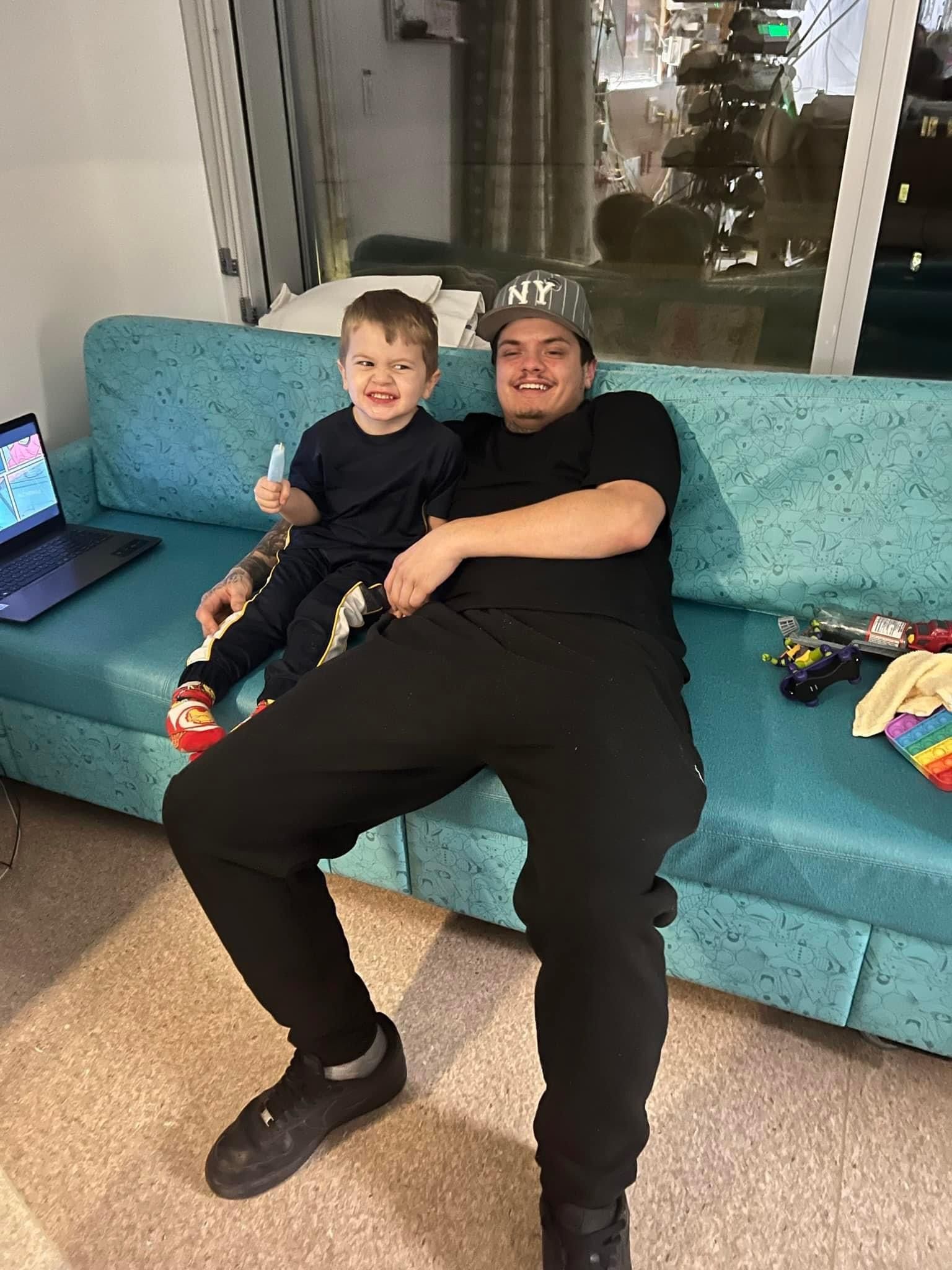 A man is sitting on a couch holding a little boy.