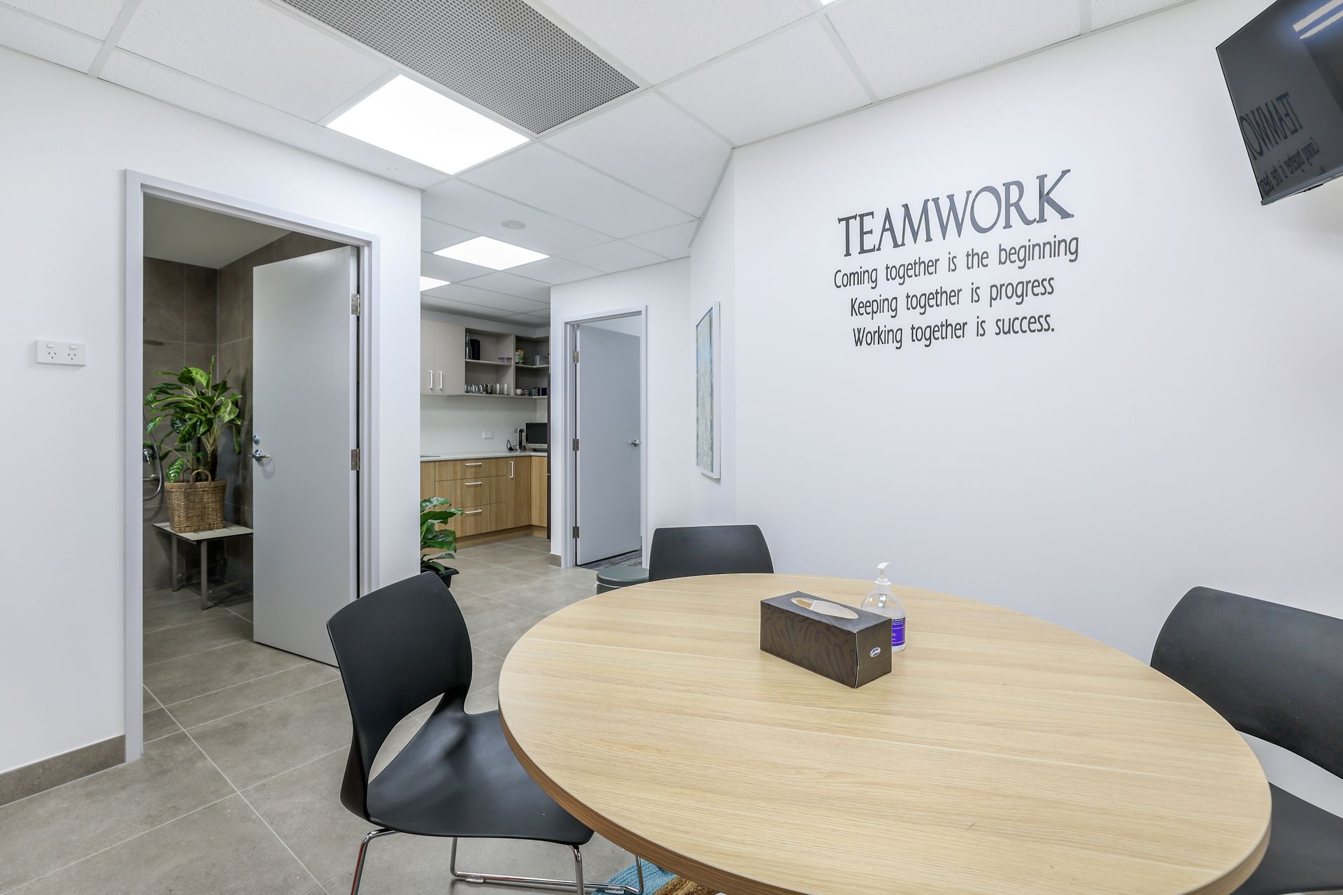 A modern office meeting room with a round table and chairs, featuring a