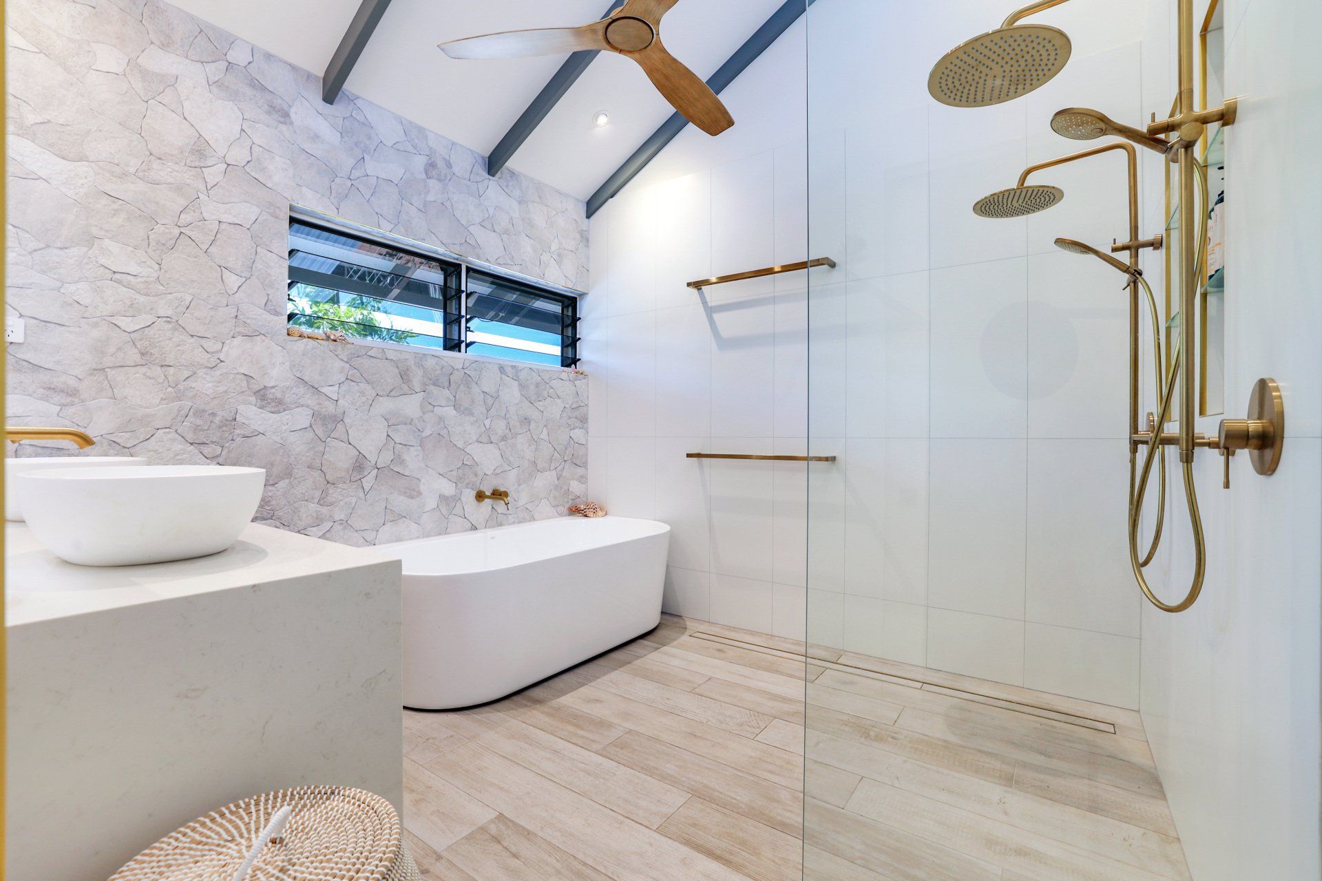 Luxurious modern bathroom with marble walls, gold fixtures, and a standalone tub.