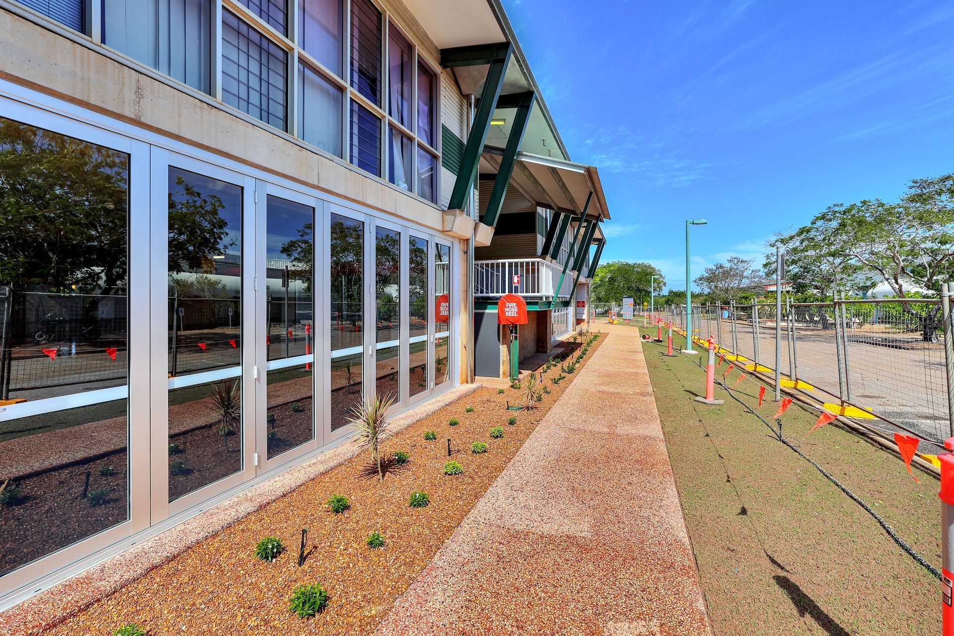 Building with large glass windows, brown walkway, blue sky.