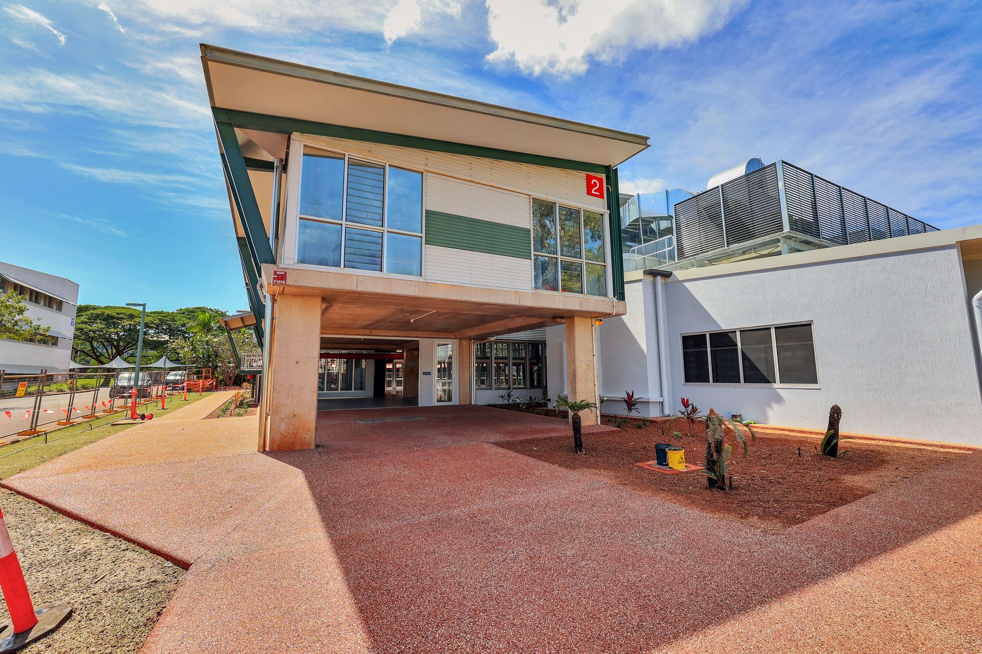 A modern building with a covered walkway; red gravel driveway, blue sky.