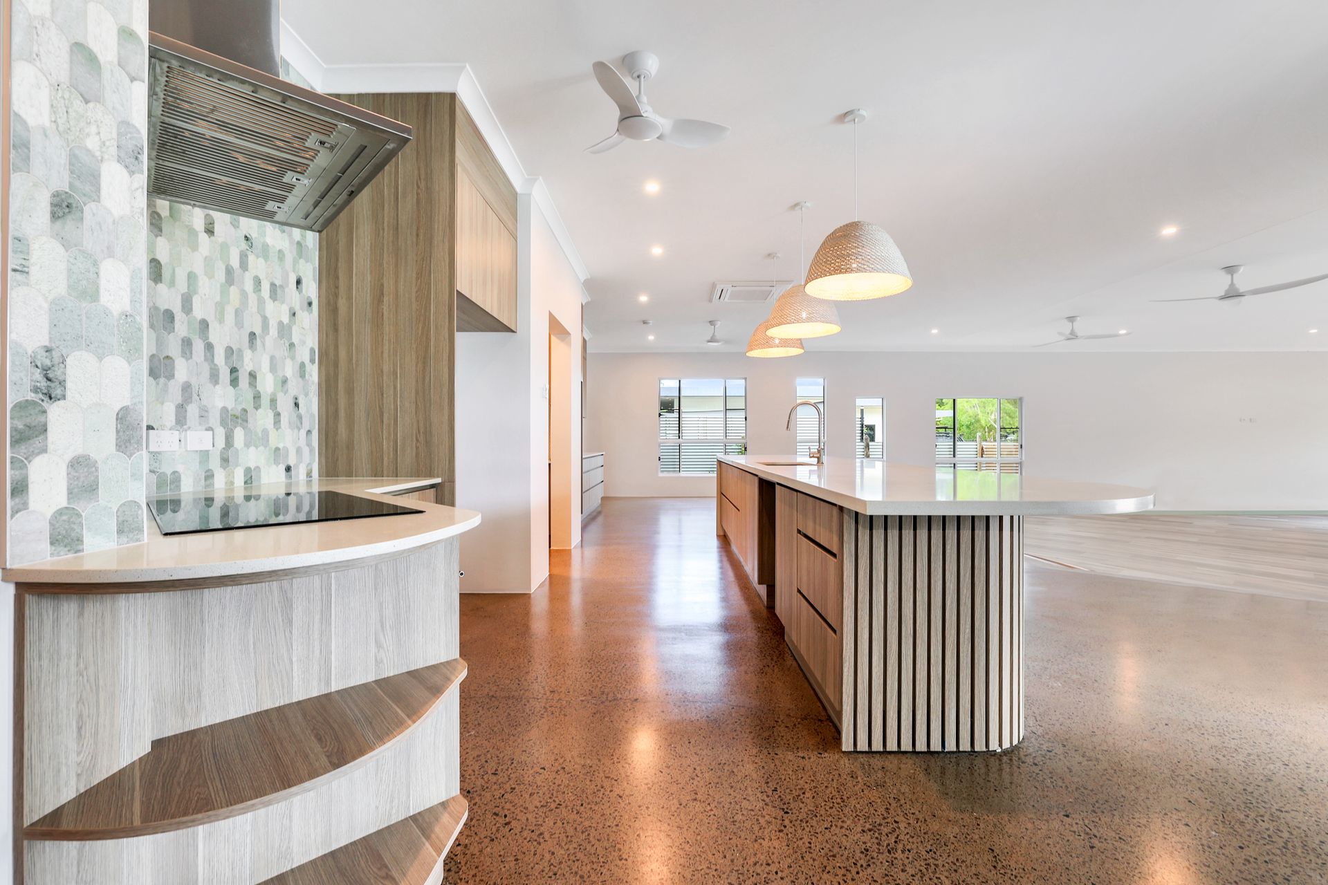 Modern kitchen with island, pendant lights, and polished concrete floor.