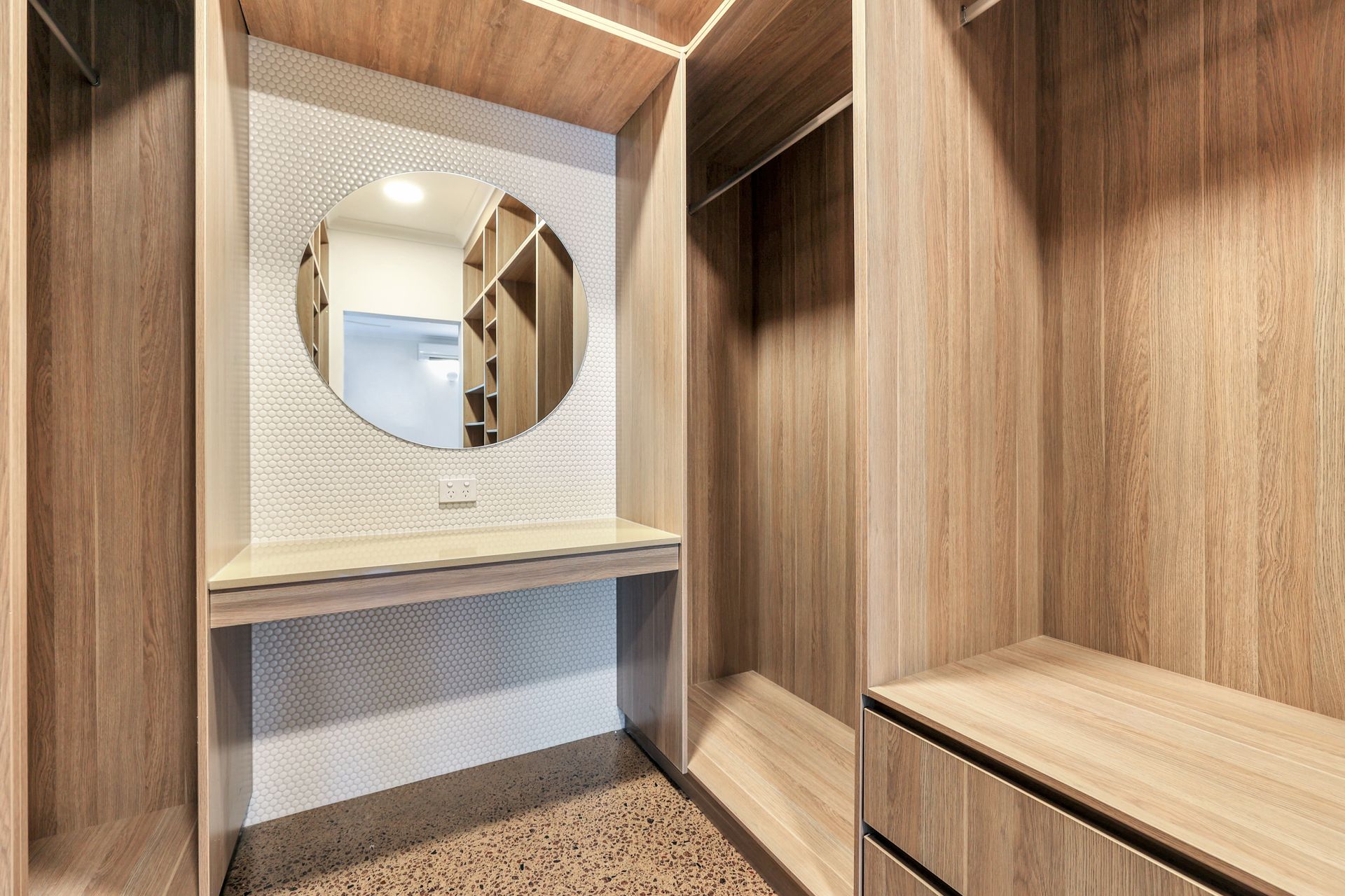 Walk-in closet with wood shelving, a vanity with a round mirror, and patterned backsplash.