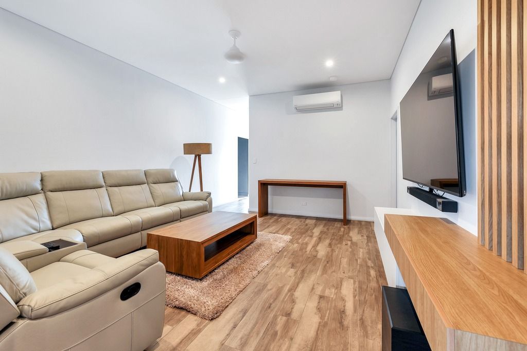 Modern living room with a beige sofa, wooden accents, and a mounted TV.