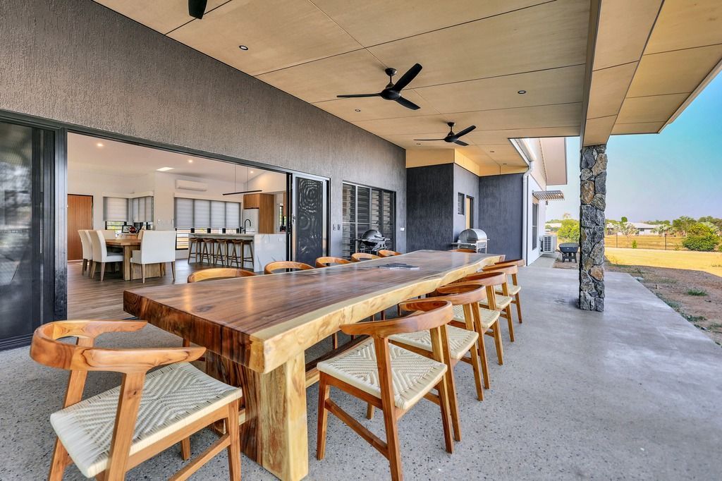 Patio with a large wooden table, chairs, and a view into a dining area.