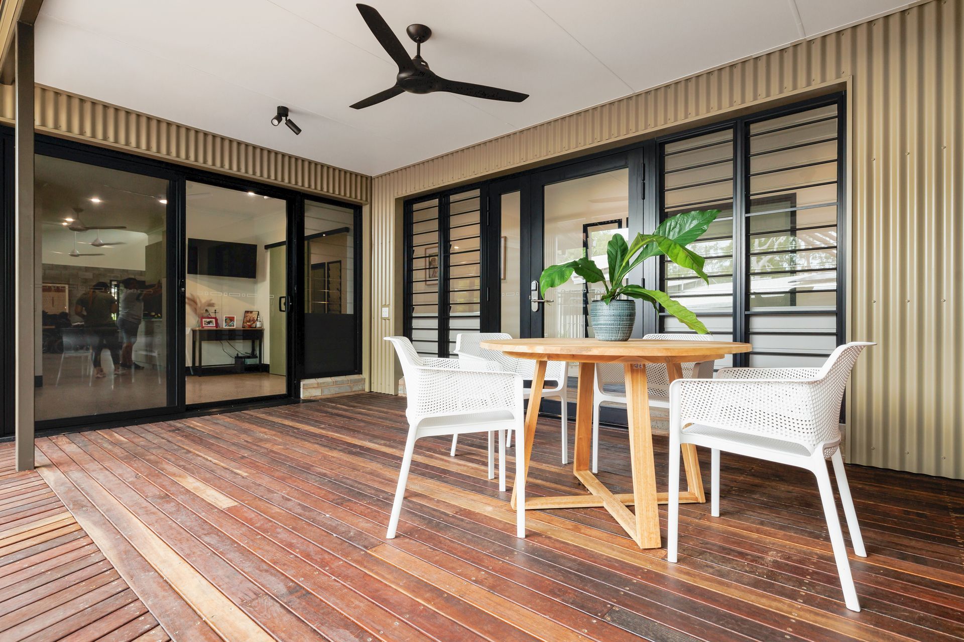 Outdoor patio with wooden deck, table and chairs. Sliding glass doors lead inside.