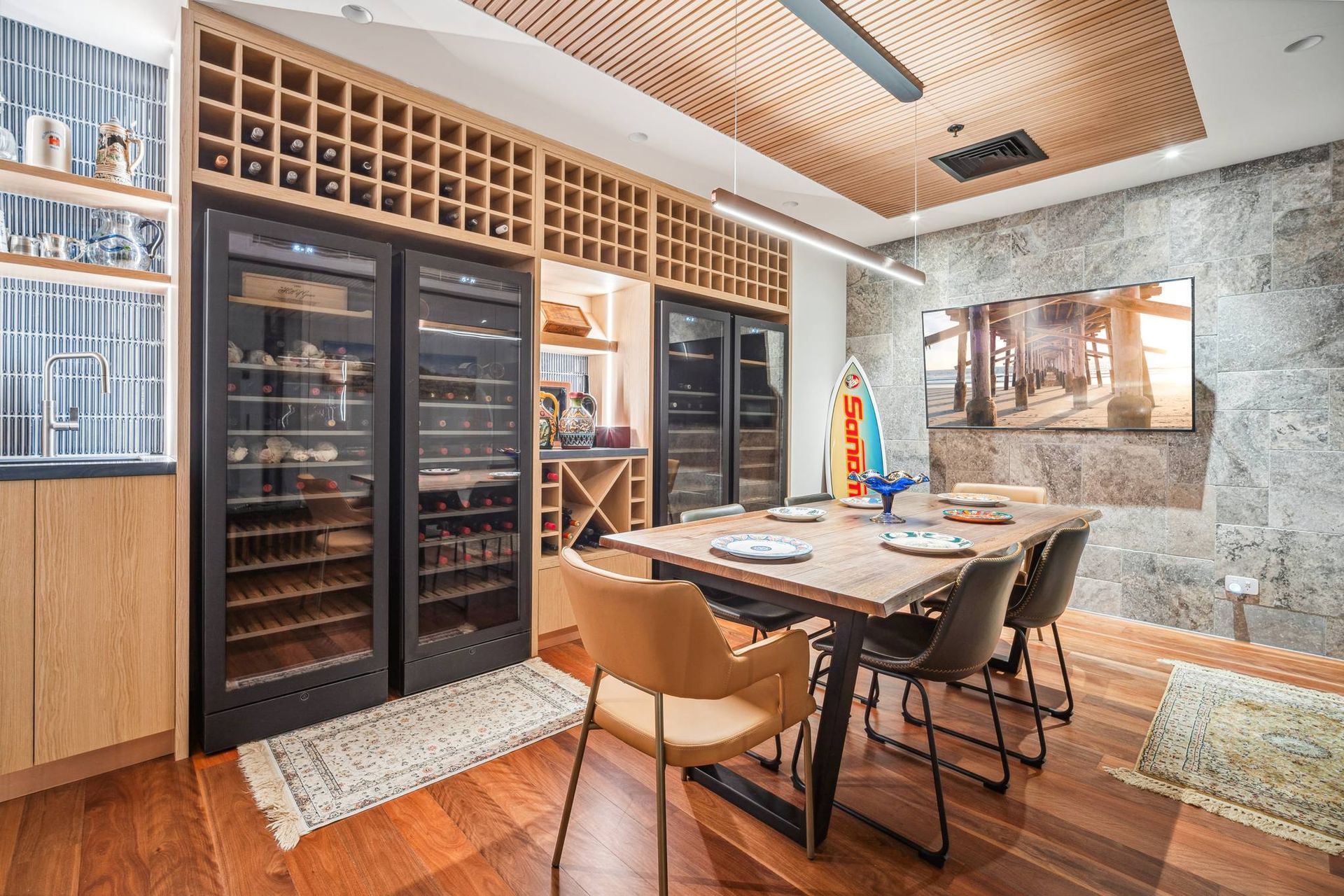 Wine room with a dining table, wooden shelves for bottles, and wine coolers.
