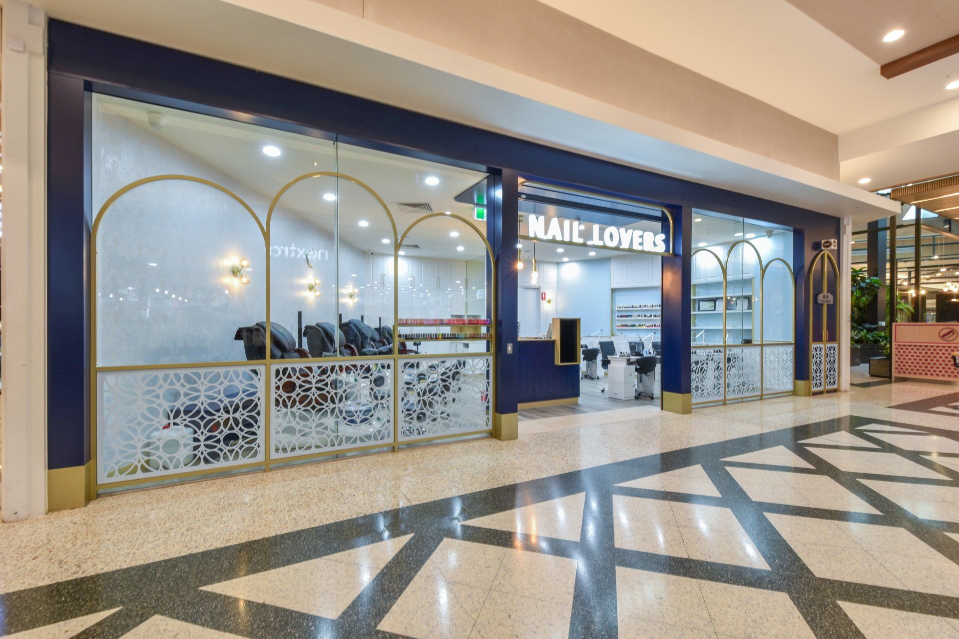 Nail Lovers salon storefront with navy blue and gold accents, inside a mall.