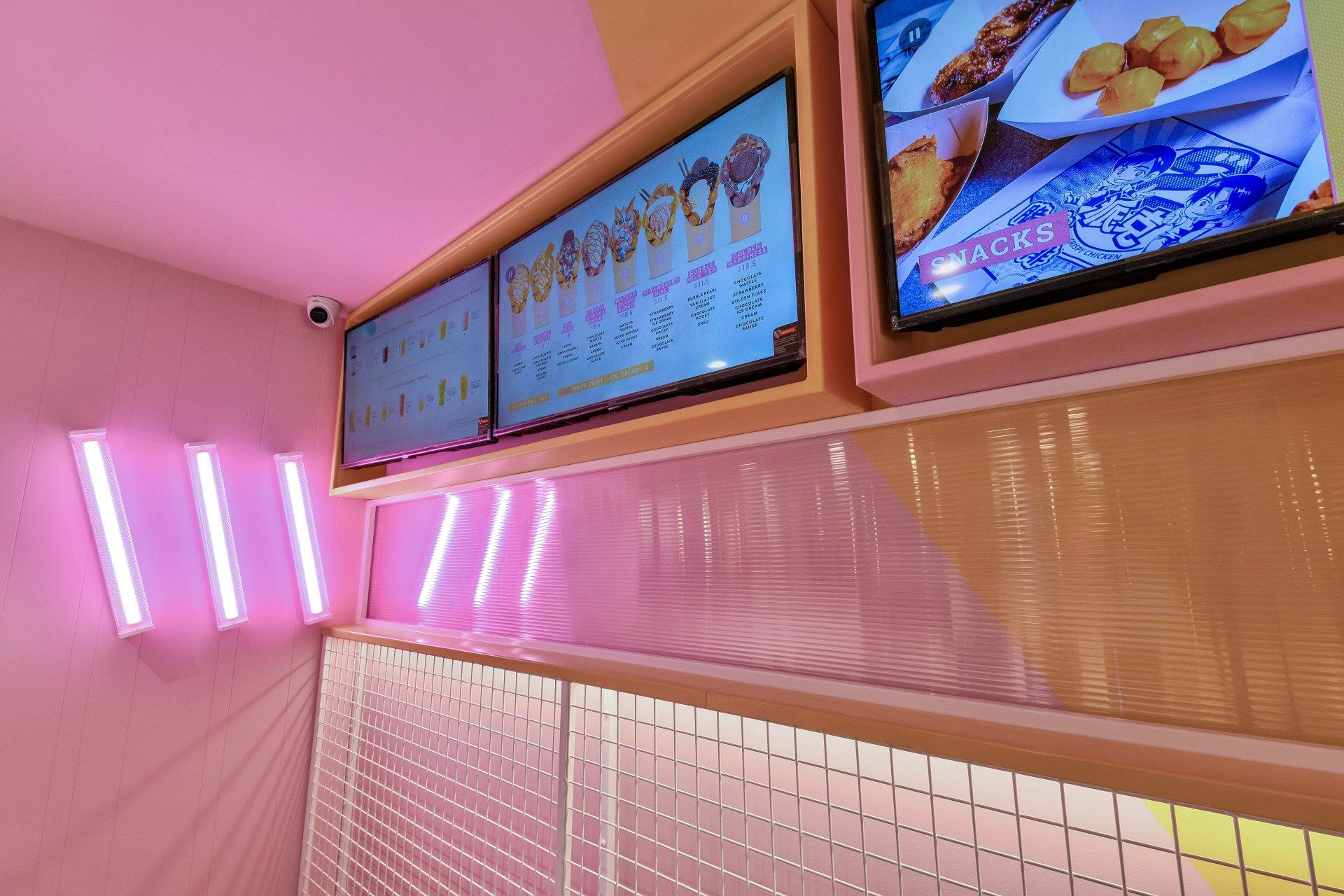 Pink-lit cafe interior with menu screens and glowing neon lights.