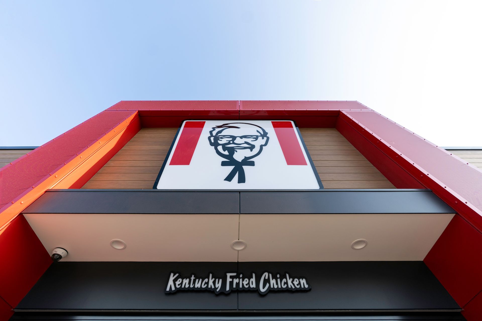 KFC restaurant exterior with Colonel Sanders logo, red accents, and Kentucky Fried Chicken sign.