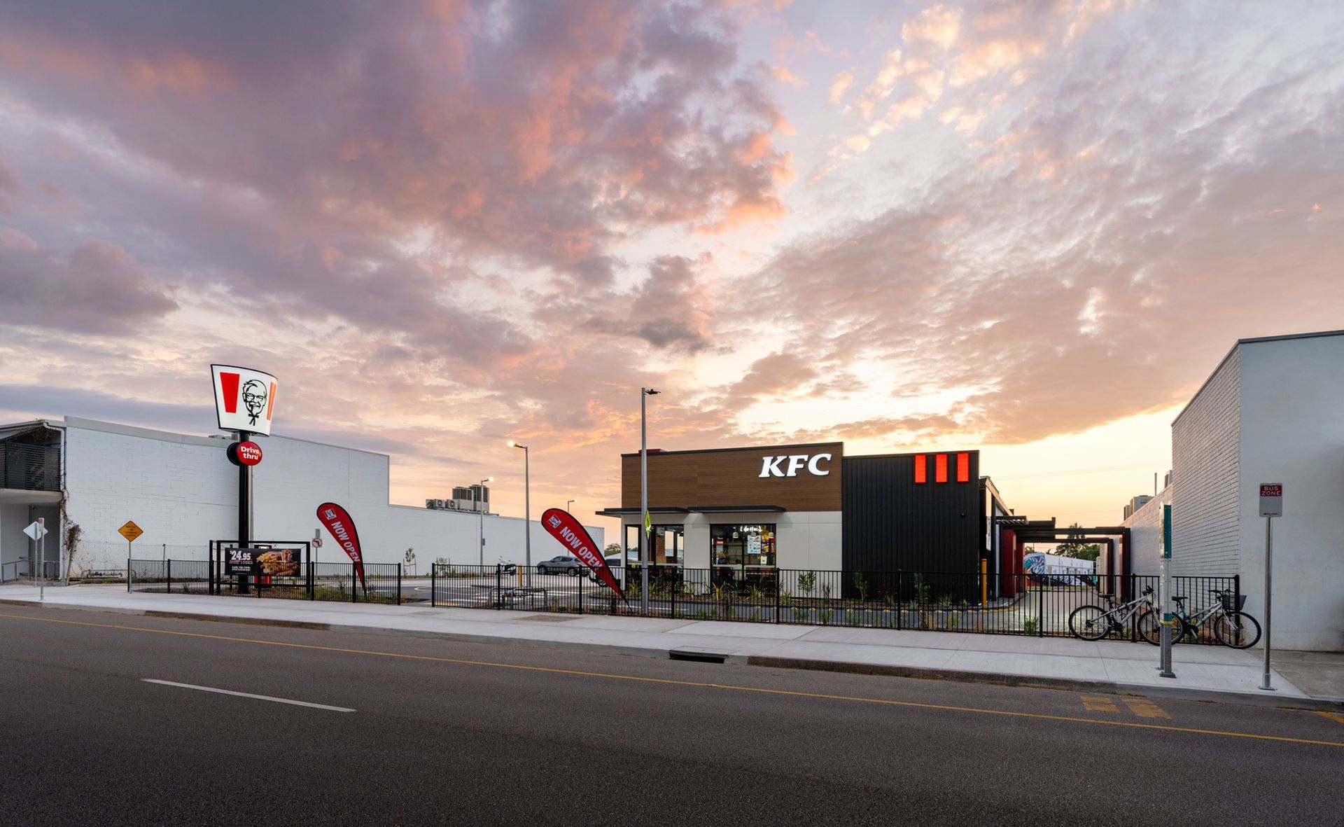 KFC restaurant at dusk with illuminated sign, in front of a colorful sky.