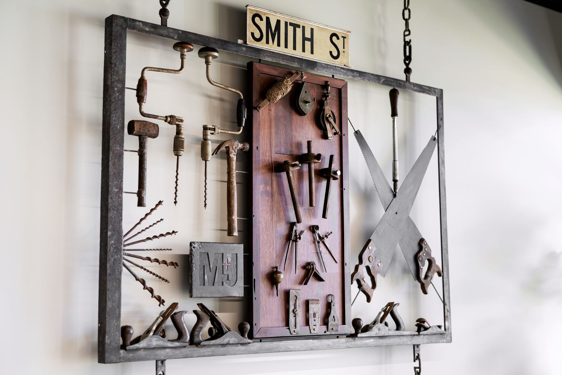 Display of vintage tools, mounted on a rectangular frame with a Smith St. sign above.