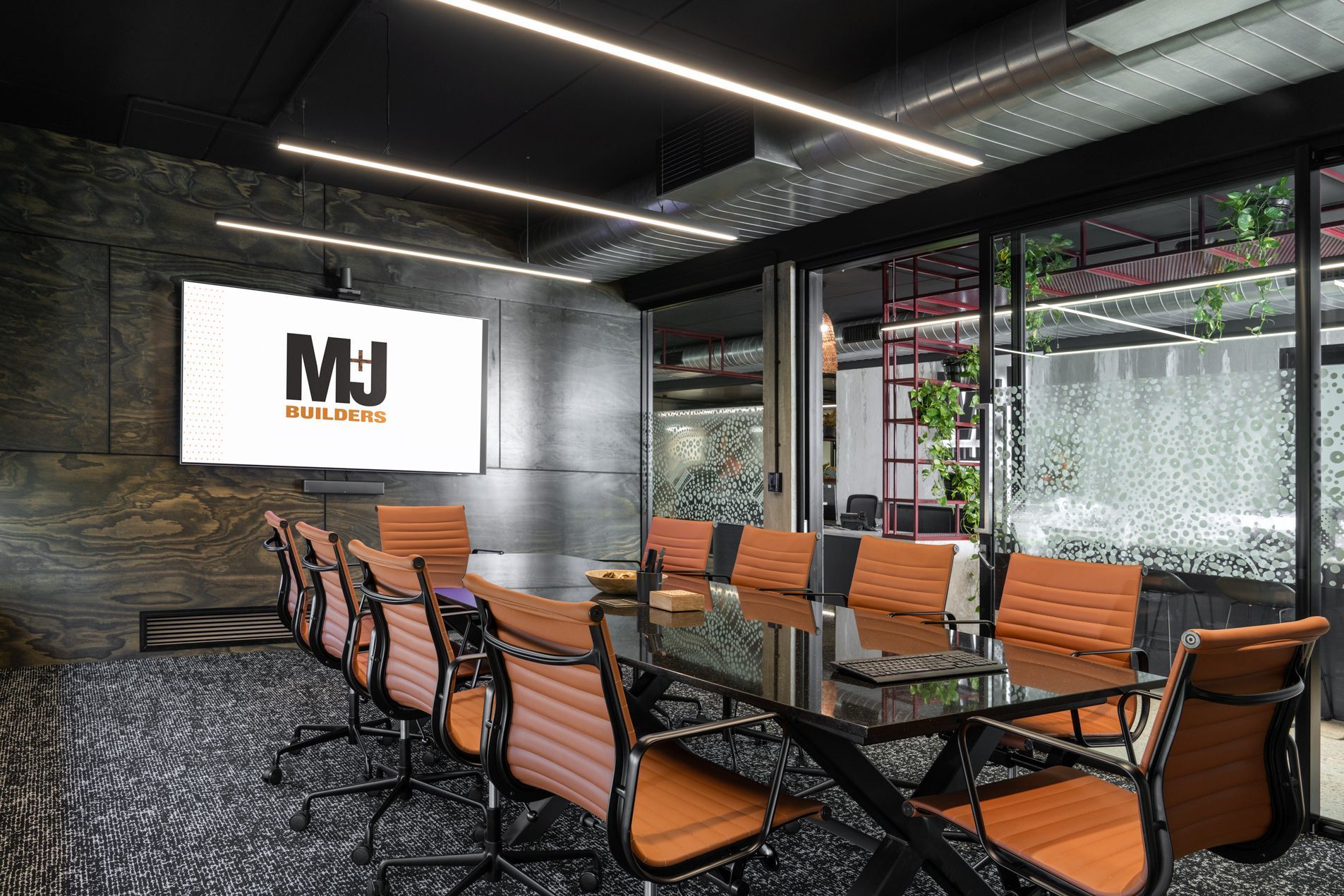 Conference room with a long table, chairs, and a screen displaying a logo.