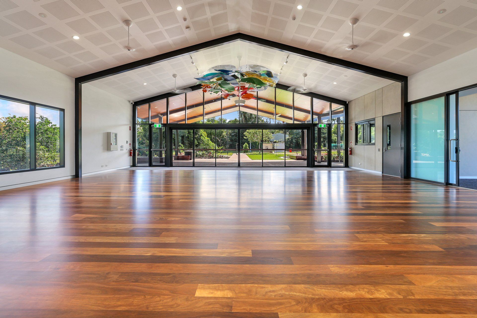 Spacious interior with wood floor, glass doors, and colorful art, leading to a bright exterior.