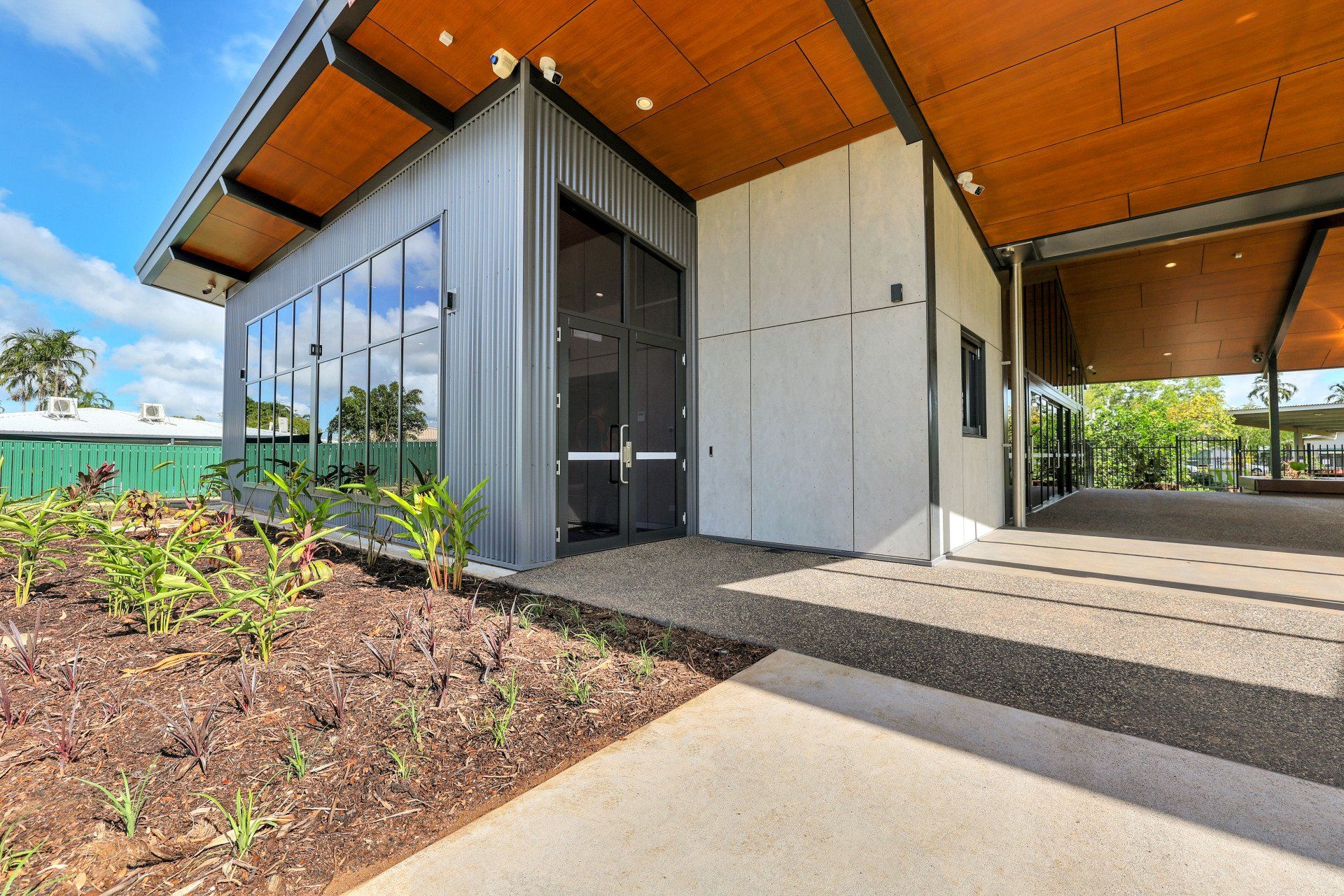 Modern building with metal siding, large windows, and covered walkway.