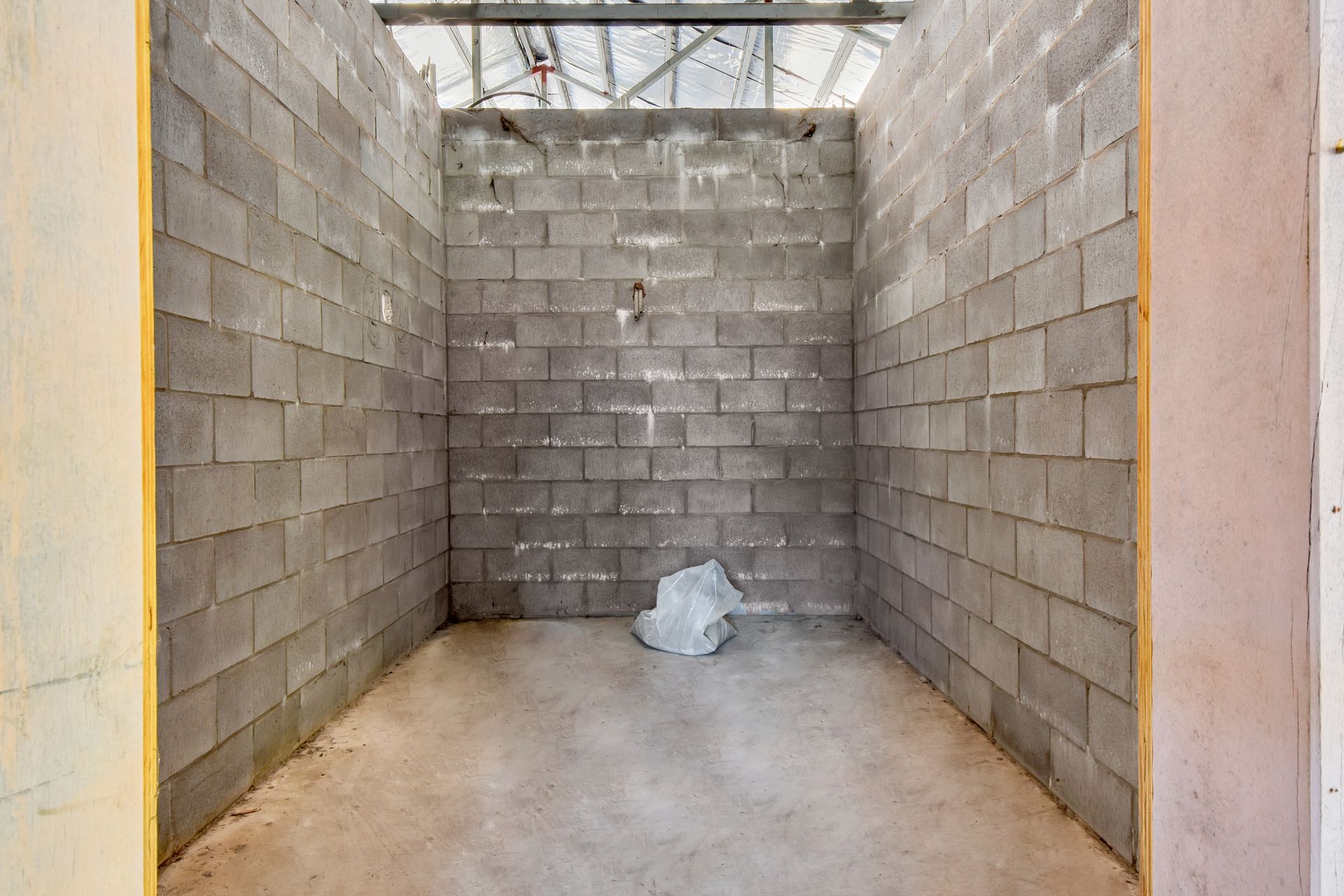 Empty room under construction with gray cinder block walls and concrete floor.