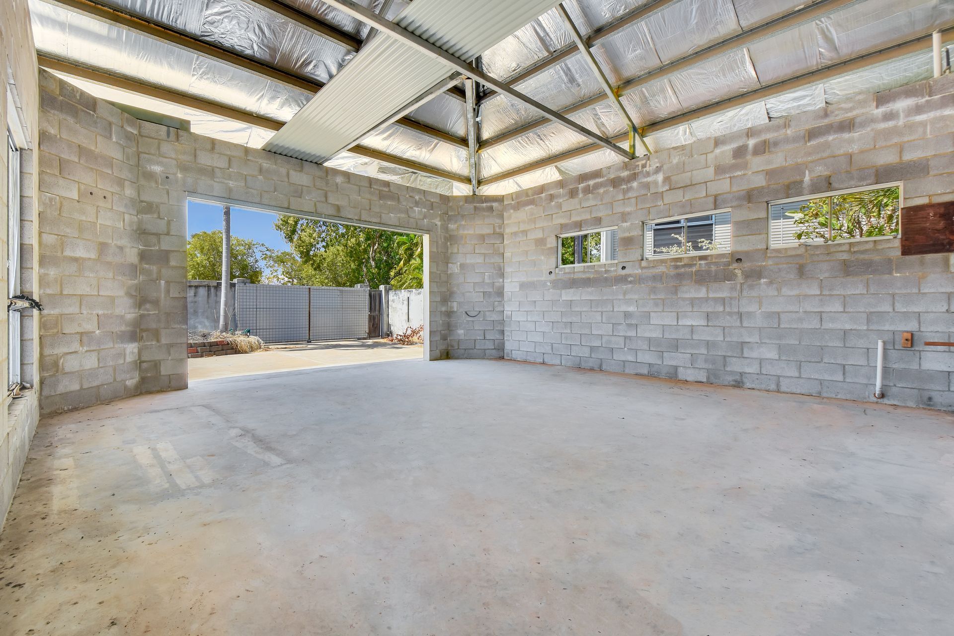 Interior of a cinder block building under construction, with a large opening and a concrete floor.