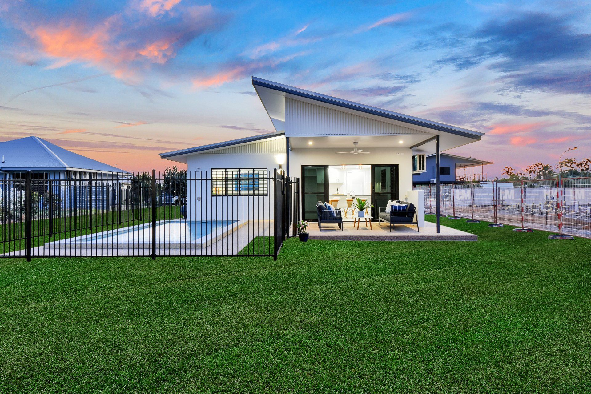 Modern white house with pool and yard, at sunset.