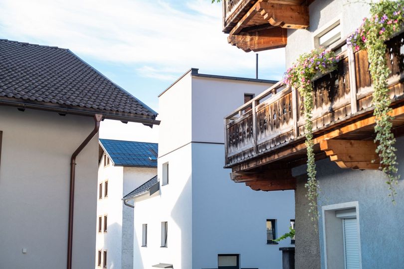 White stucco houses with red-tiled roofs and wooden balconies in a sunny village street