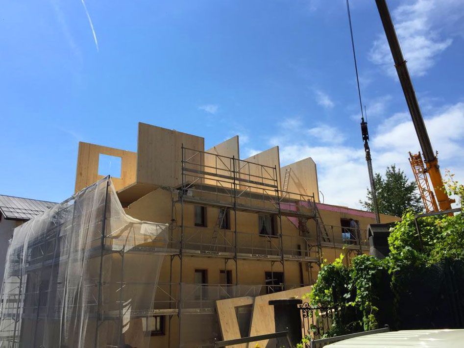 Construction scaffolding around a tan building under a bright blue sky