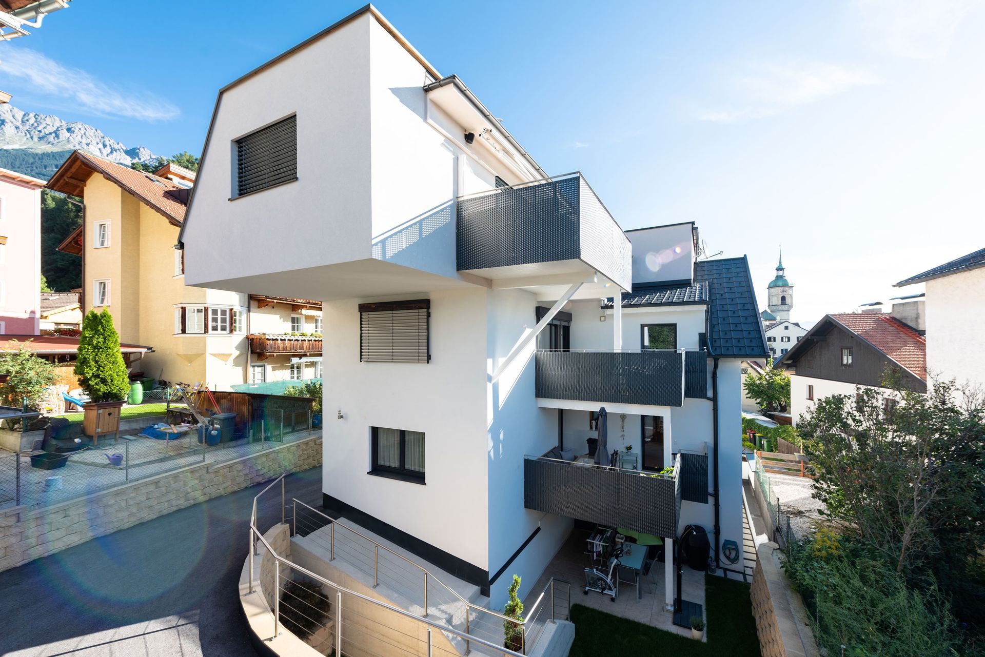 Modern white apartment building with balconies in a sunny residential neighborhood