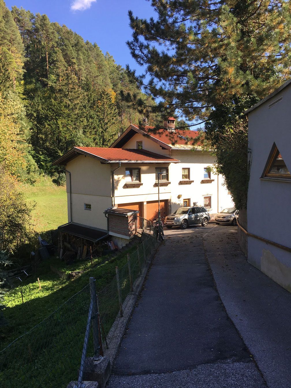 Steep path leading to a white house with red roof in a wooded hillside village